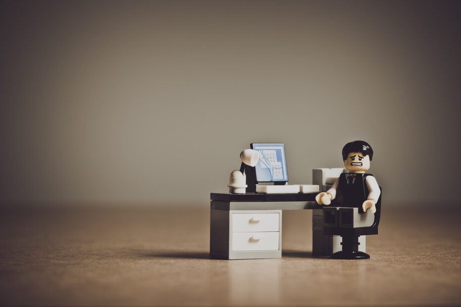 Lego-Männchen mit verzweifelter Miene vor einem Schreibtisch mit PC.